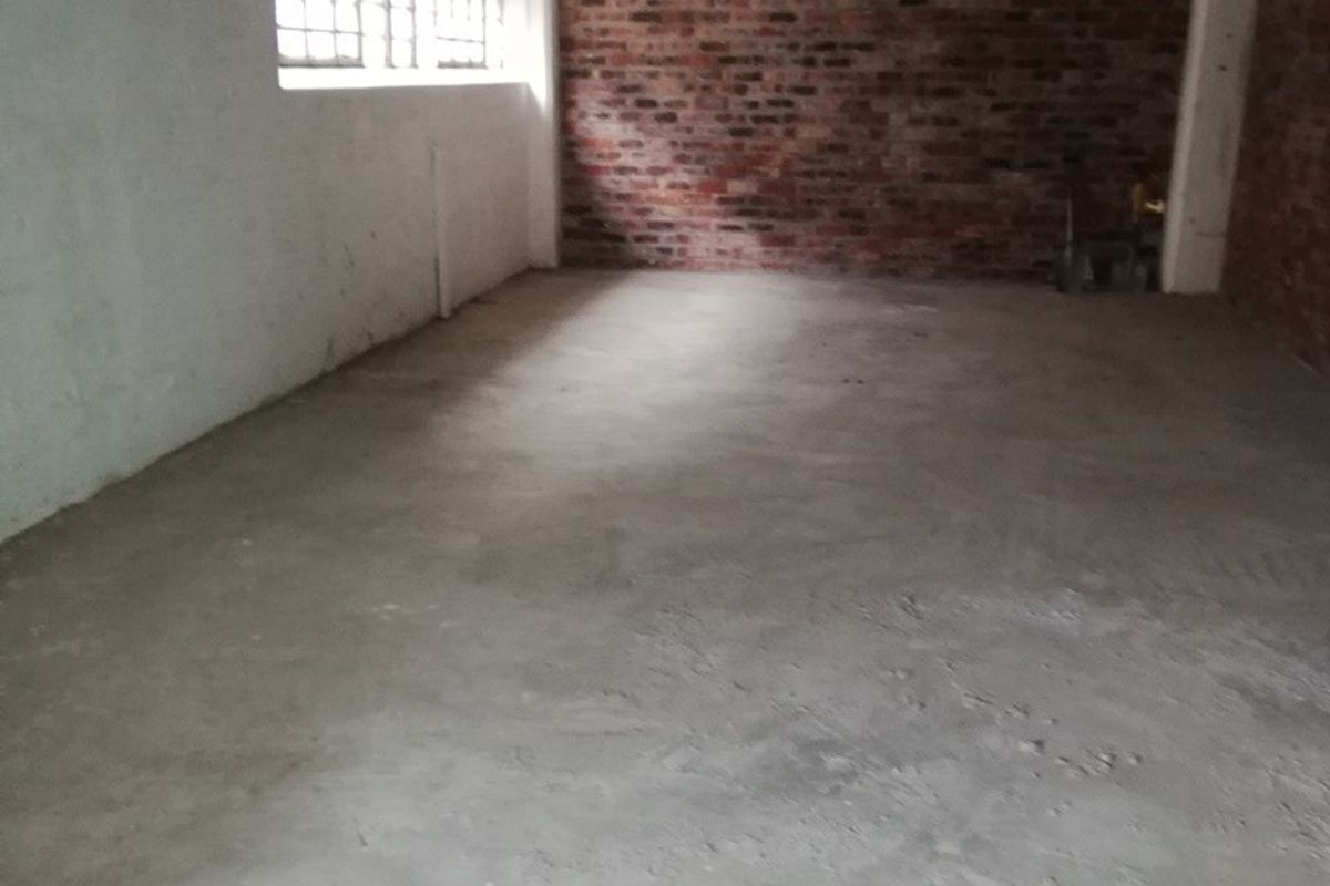 An unfinished utility space featuring exposed brick walls, a concrete floor, and high-level windows, offering a blank canvas for renovation or storage use.