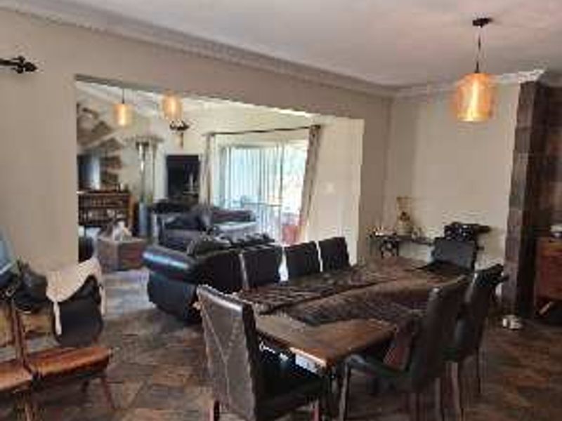 Spacious open-plan living and dining area featuring tiled flooring, coved cornicing, and direct access to an outdoor patio through sliding glass doors.