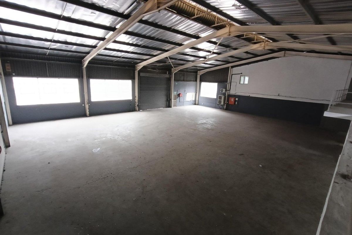 Spacious industrial warehouse unit featuring high ceilings, steel portal frame construction, concrete flooring, and a large roller shutter door for easy access.