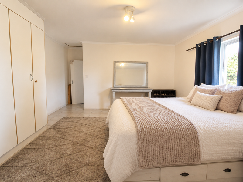 A well-maintained bedroom featuring built-in cupboards, tiled flooring, and neutral wall finishes, offering a clean and functional living space.