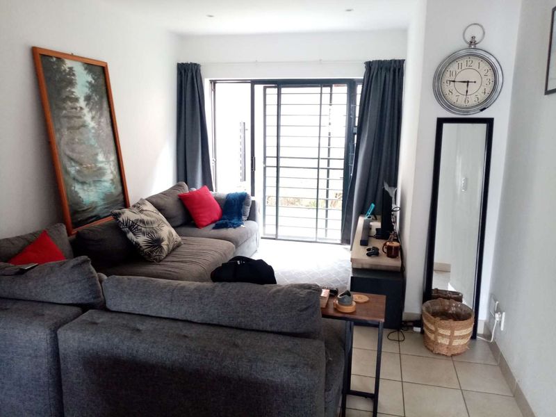 A living room featuring tiled flooring, recessed lighting, and a sliding glass door with a security gate leading to an outdoor area.