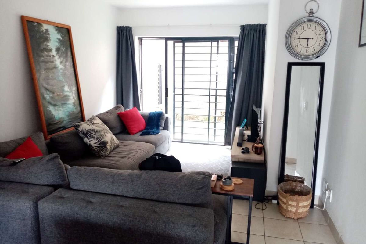 A living room featuring tiled flooring, recessed lighting, and a sliding glass door with a security gate leading to an outdoor area.