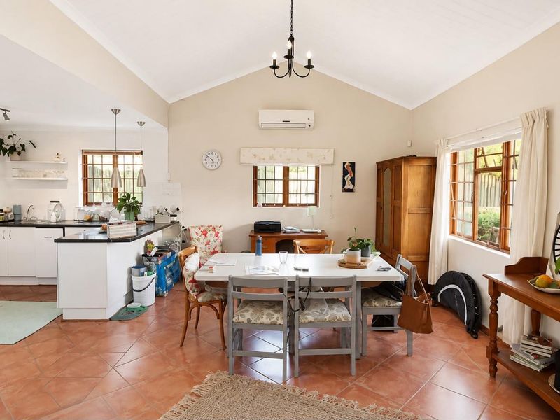 Spacious open-plan living and dining area featuring vaulted ceilings, tiled flooring, and a functional kitchen with a central island and ample cabinetry.