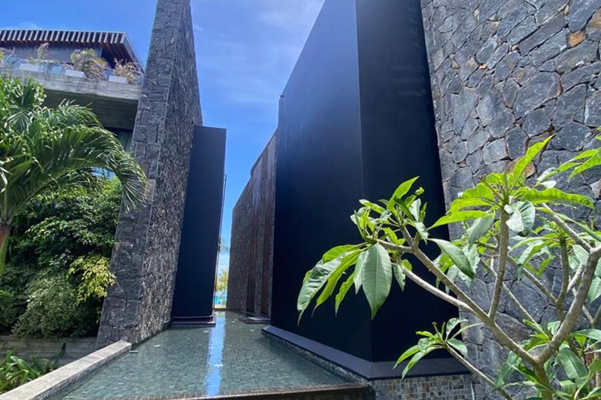 A modern architectural exterior featuring striking dark stone cladding, smooth black feature walls, and a tranquil reflective water feature.