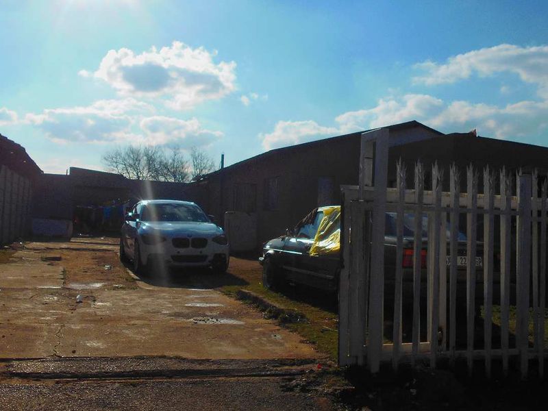 Front exterior view of the property featuring a concrete driveway, perimeter wall, and metal security gate entrance.