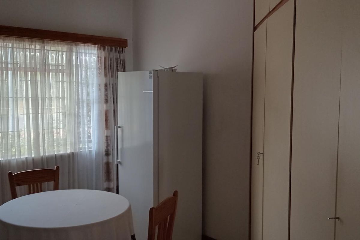 A bedroom featuring built-in cupboards and a window fitted with security bars, offering a functional space with neutral finishes.