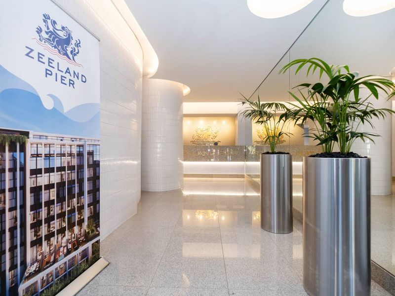 Modern apartment building entrance lobby featuring polished tile flooring, curved tiled walls, recessed lighting, and a professional reception area.