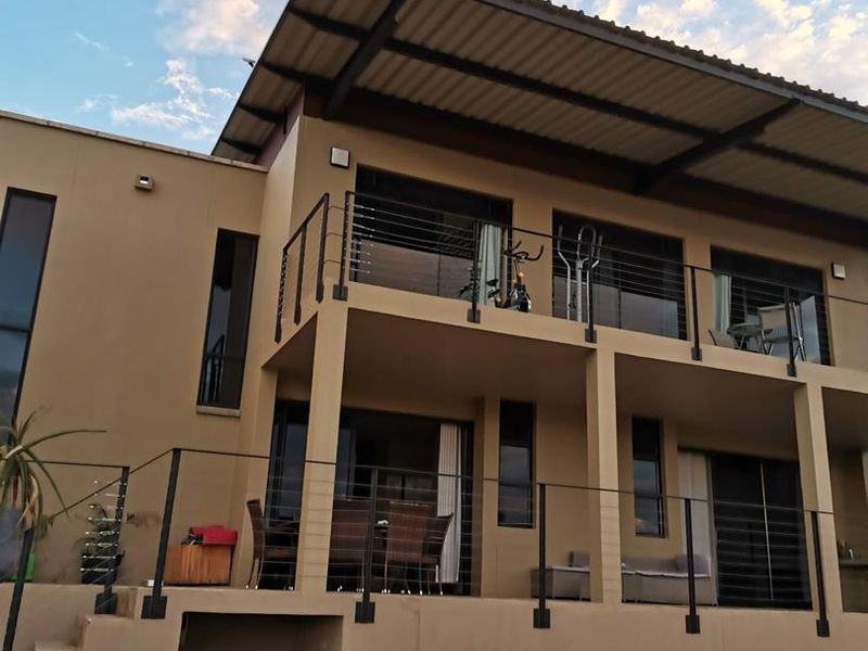 Rear elevation of a modern townhouse featuring a double-story design with balconies, cable railings, and a paved patio area.