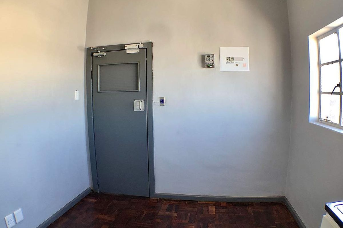 A vacant utility room featuring parquet flooring, a secure steel door, and an integrated electrical distribution board.