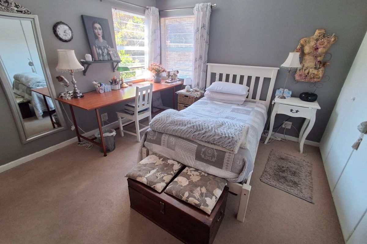 A cozy bedroom featuring neutral wall tones, carpeted flooring, and a built-in wardrobe, offering a functional and comfortable living space.