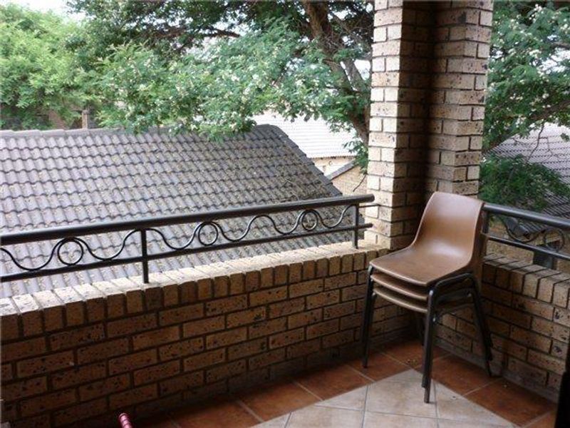 A private balcony featuring a brick balustrade with metal railing and tiled flooring, offering an elevated outdoor space.