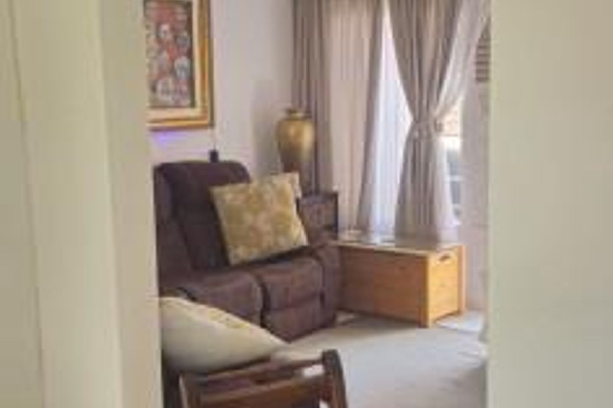A view into a living room area featuring tiled flooring and ceiling-mounted lighting, viewed through an arched doorway from an adjacent space.