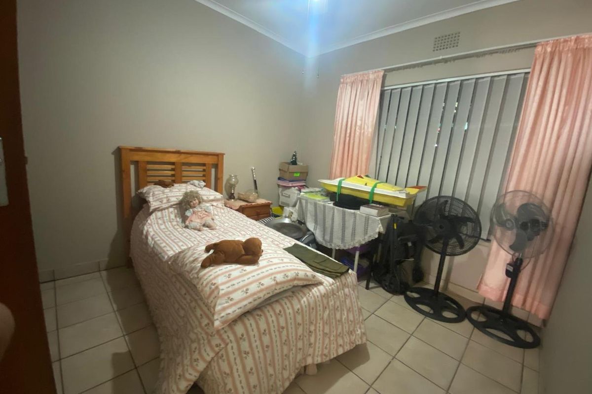 A bedroom featuring tiled flooring, a window with vertical blinds, and a ceiling-mounted light fixture.