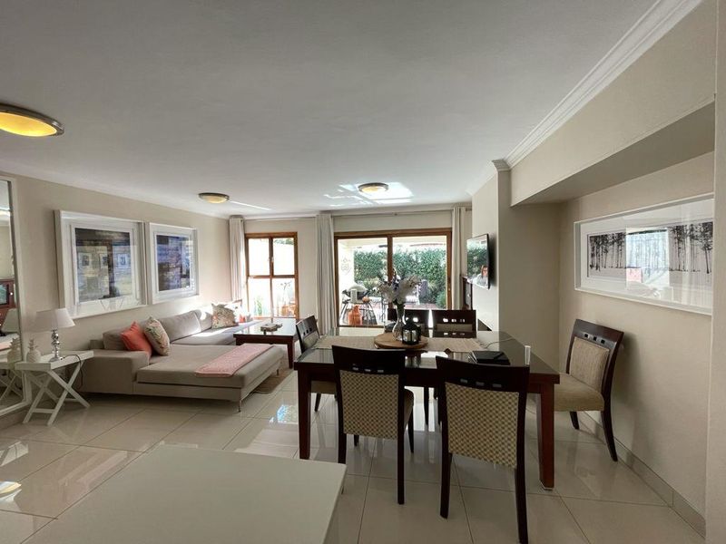 Spacious open-plan living and dining area featuring neutral tiled flooring, recessed lighting, and large sliding doors providing access to the outdoor patio.