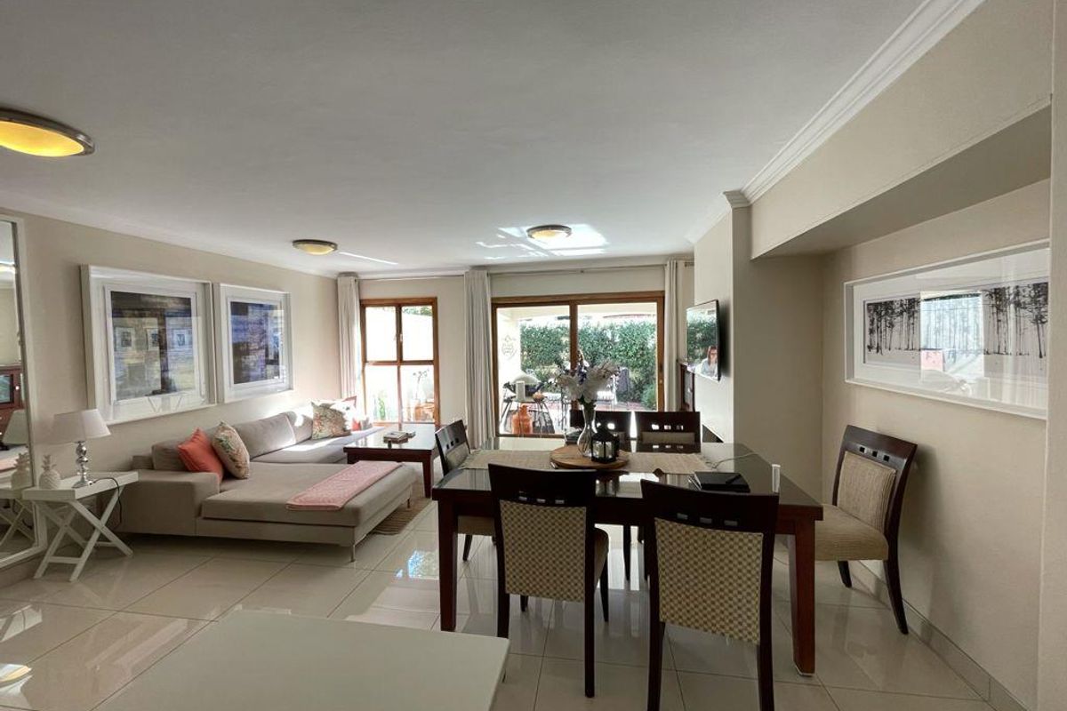 Spacious open-plan living and dining area featuring neutral tiled flooring, recessed lighting, and large sliding doors providing access to the outdoor patio.