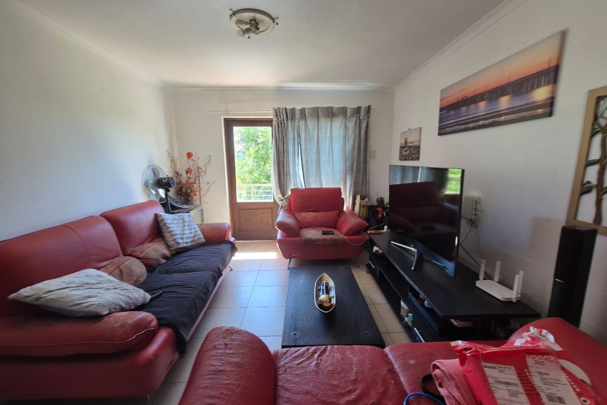 A living room featuring tiled flooring and a glass panel door providing access to an outdoor area.