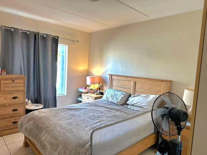 A standard bedroom featuring tiled flooring and a window with curtain rod, offering a functional space for rest.