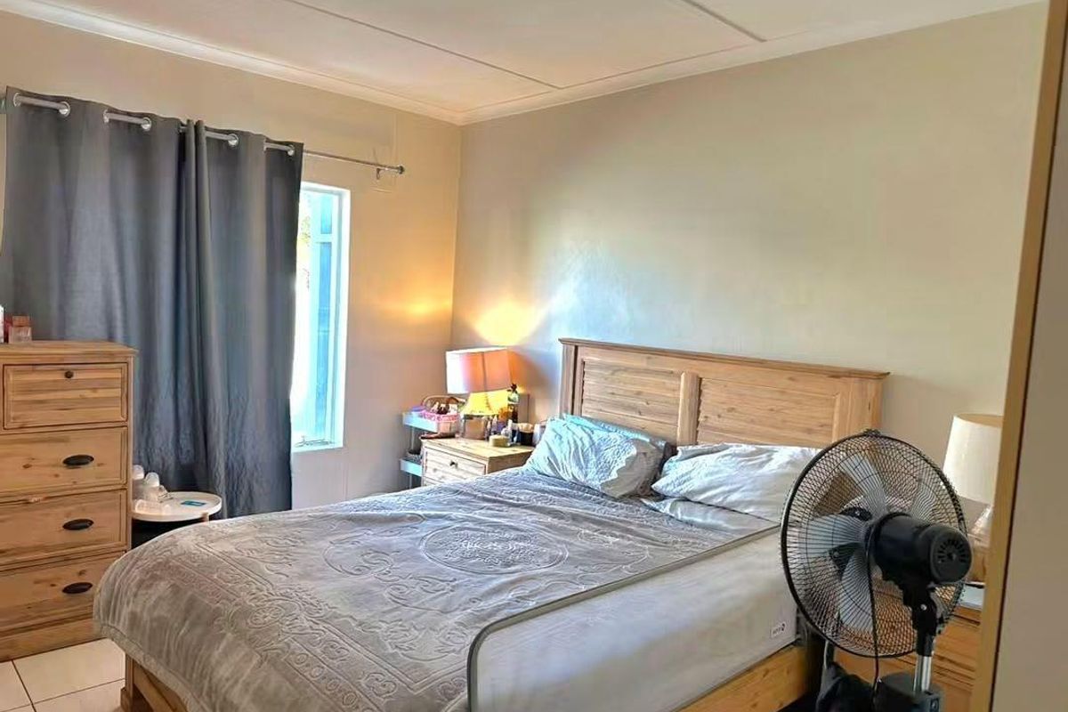 A standard bedroom featuring tiled flooring and a window with curtain rod, offering a functional space for rest.