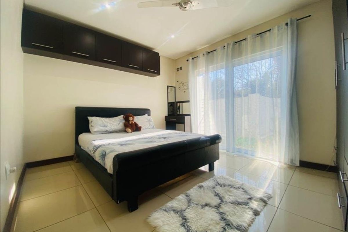 A well-lit bedroom featuring tiled flooring, built-in overhead cabinetry, and sliding glass doors providing access to the exterior.