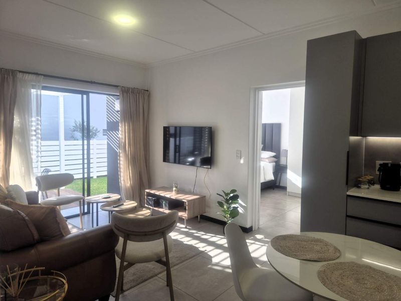 Modern open-plan living area featuring tiled floors, sleek kitchen cabinetry, and a sliding glass door leading to an outdoor patio space.