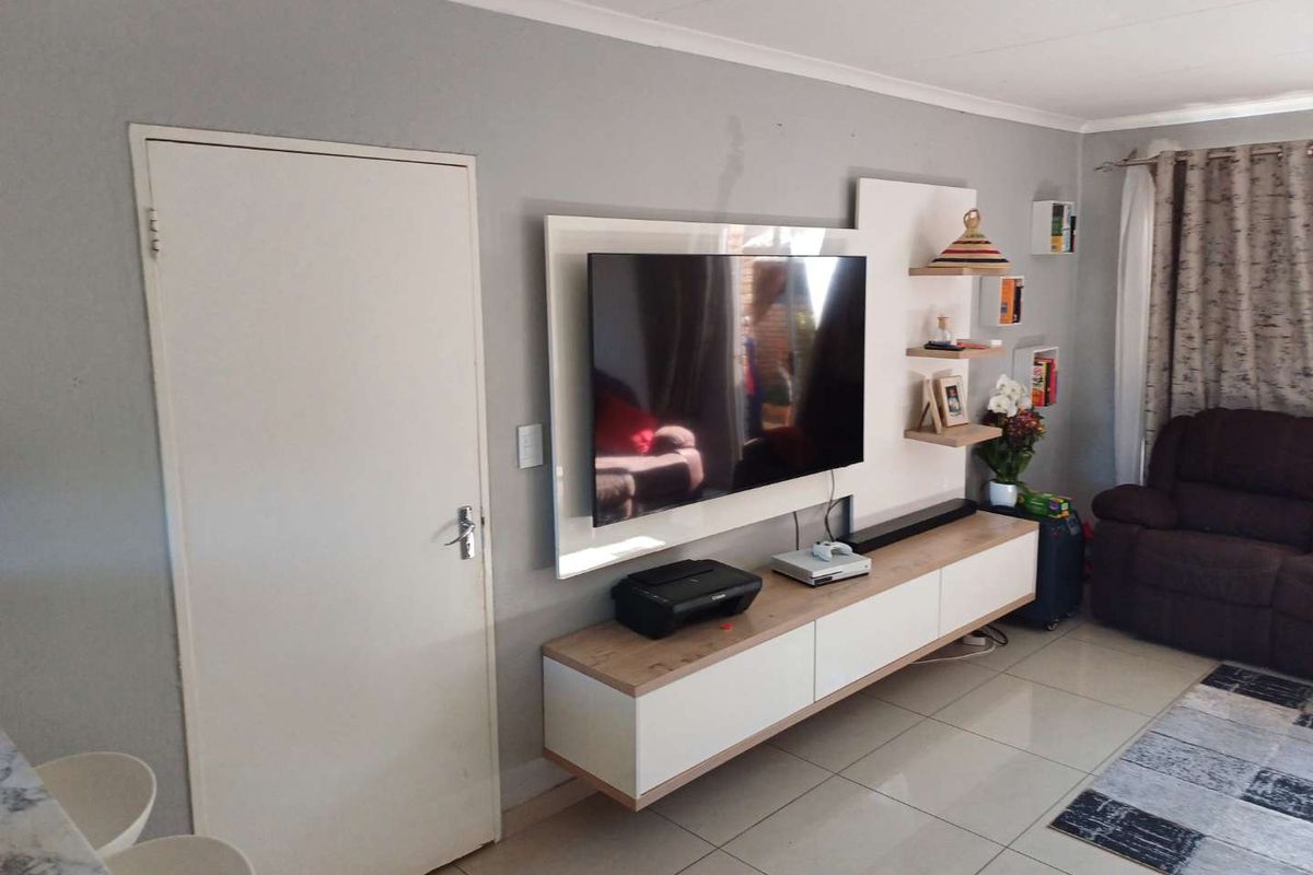 A modern living room featuring a sleek, wall-mounted media console with integrated shelving and neutral tiled flooring.