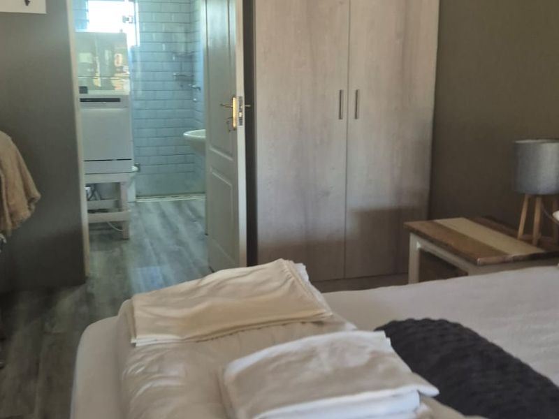 A comfortable bedroom featuring a built-in wardrobe and direct access to an en-suite bathroom with modern subway tile finishes.