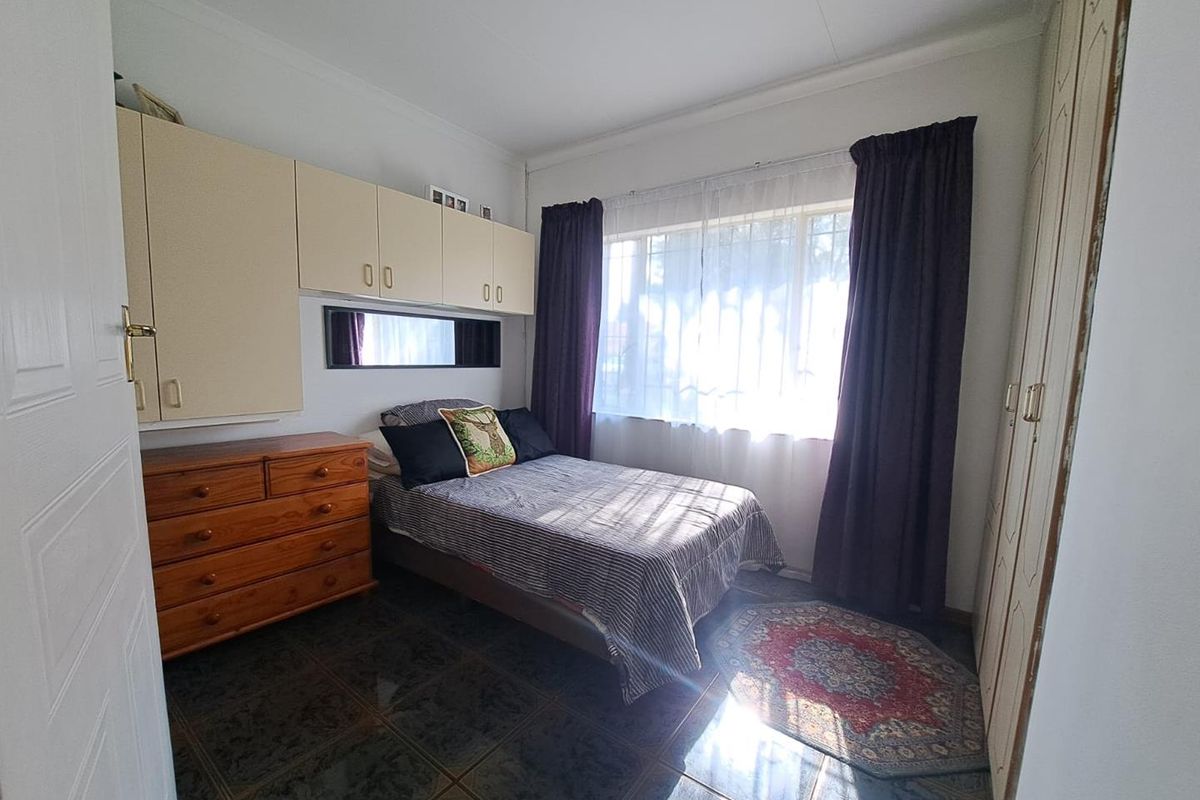 A bedroom featuring built-in cabinetry, tiled flooring, and a window with curtains.