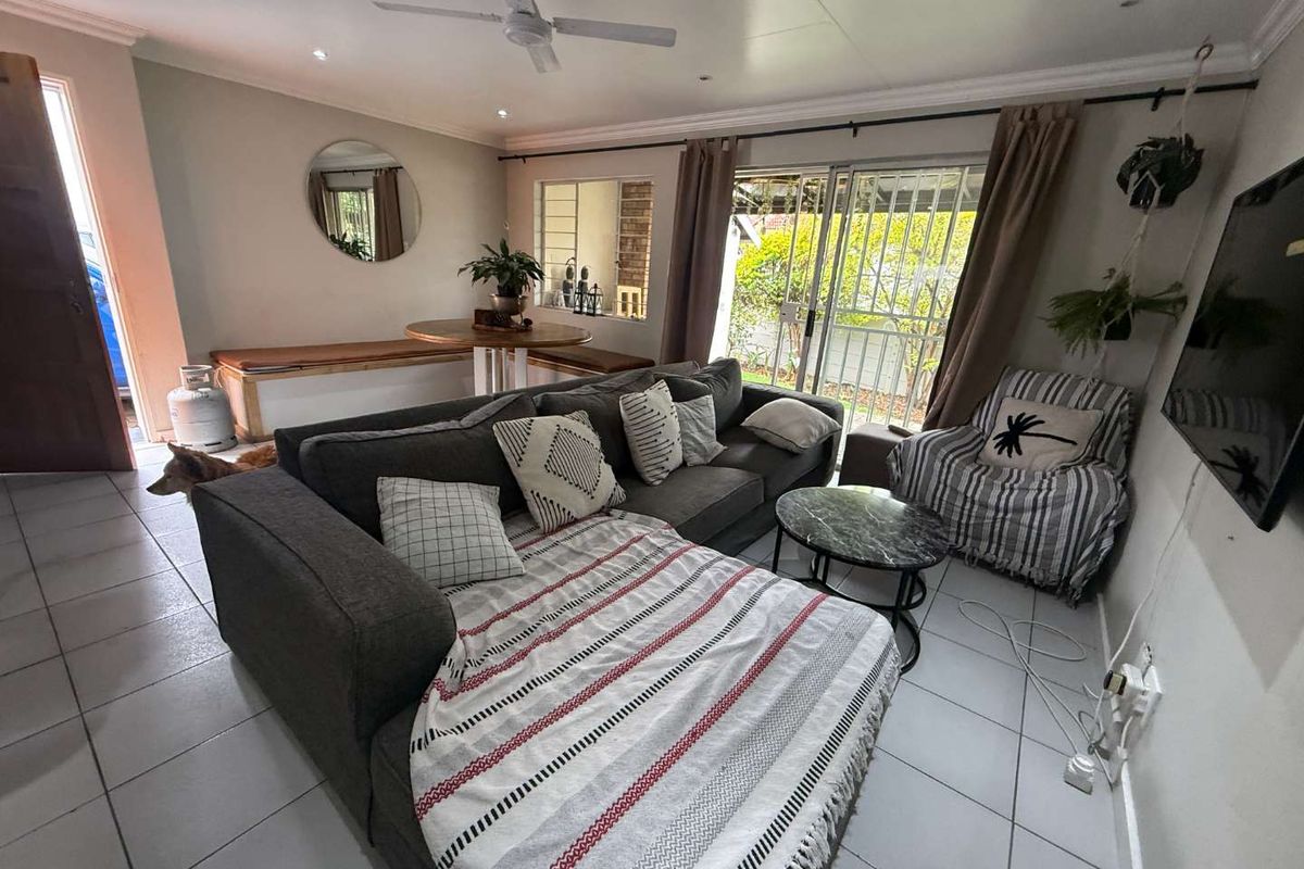 A comfortable living room featuring tiled flooring, a ceiling fan, and sliding glass doors that provide access to the outdoor area.