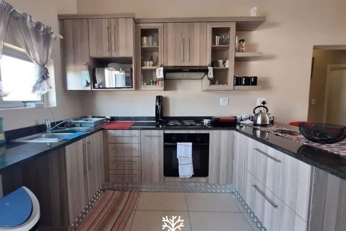 A functional kitchen featuring wood-look cabinetry, granite countertops, a built-in oven with gas hob, and tiled flooring.