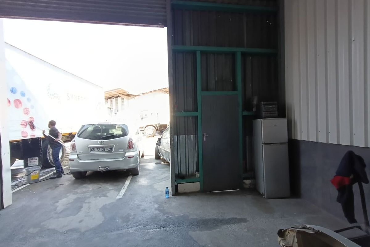 Industrial garage space featuring a large roller shutter door, concrete flooring, and metal wall cladding, suitable for vehicle maintenance or storage.
