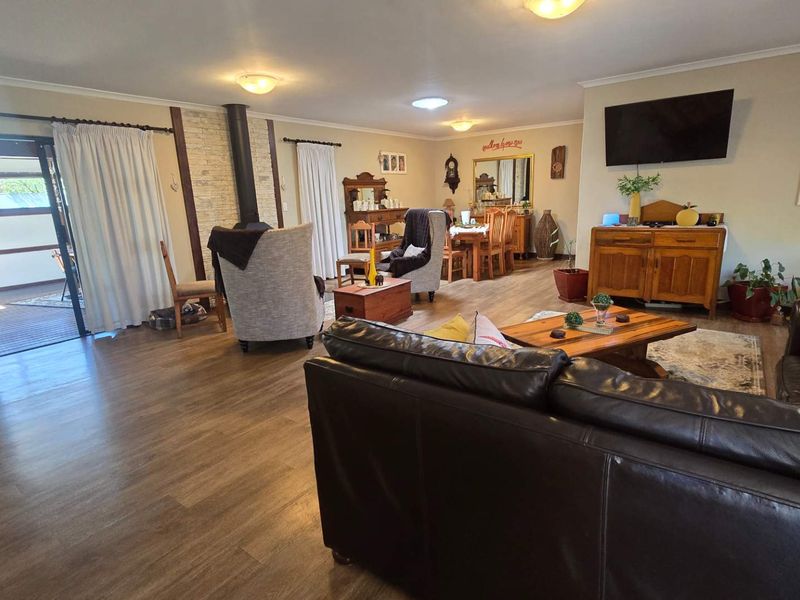 Spacious open-plan living and dining area featuring laminate flooring, a stone-surround wood-burning fireplace, and direct access to an outdoor patio.
