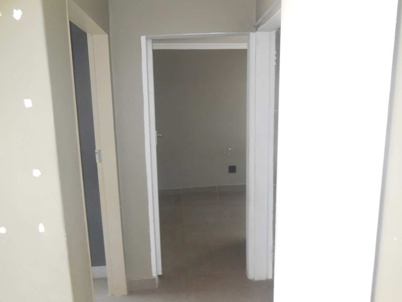 A view through a hallway showing multiple doorways and unfinished wall surfaces, indicating a property currently undergoing maintenance or renovation.