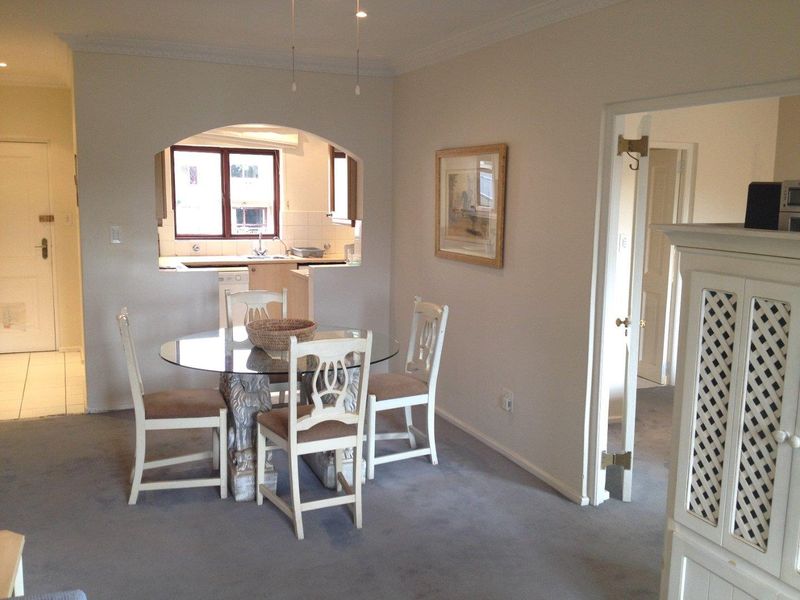Open plan dining area featuring a kitchen pass-through archway, neutral wall finishes, and carpeted flooring, connecting to adjacent living and kitchen spaces.