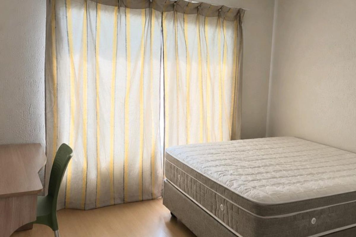 A functional bedroom featuring laminate flooring, neutral walls, and a ceiling light fixture, providing a clean and simple space.