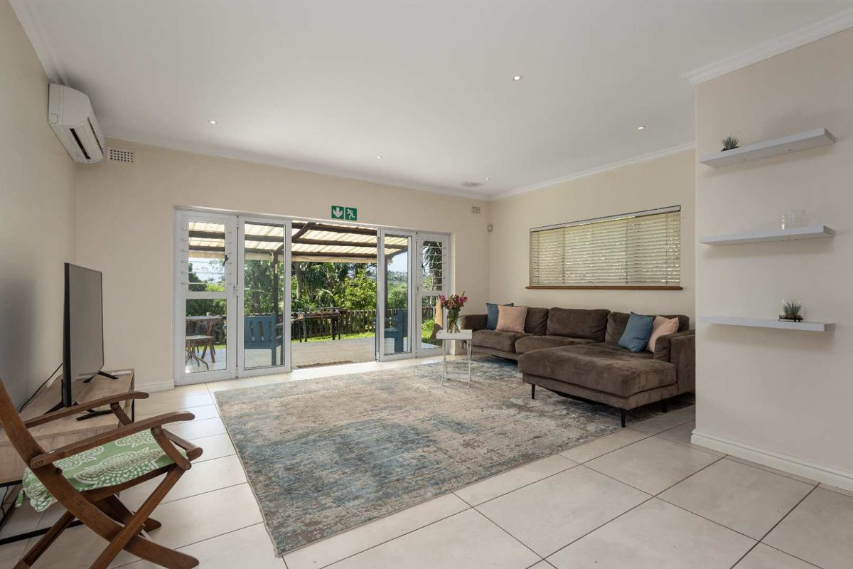 Spacious living room featuring tiled flooring, recessed lighting, wall-mounted air conditioning, and large glass sliding doors opening onto a covered patio.