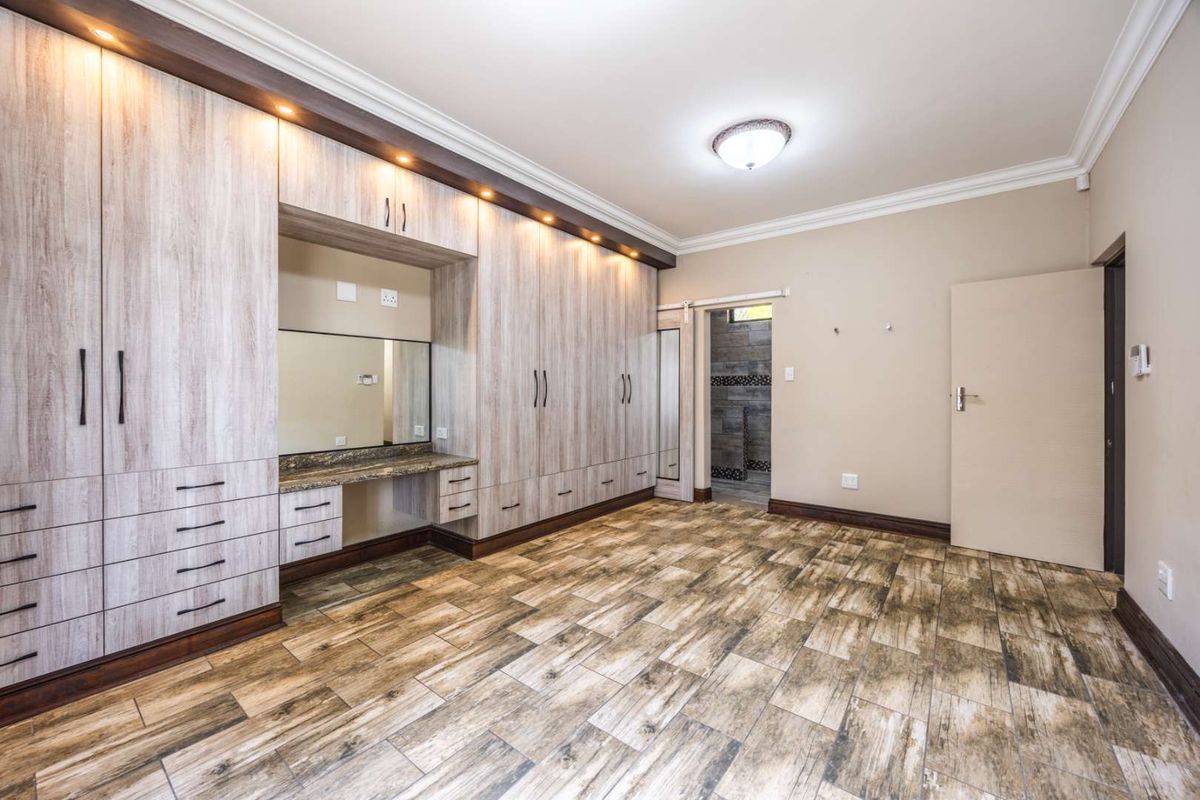 Spacious bedroom featuring extensive built-in cabinetry with an integrated vanity, modern tiled flooring, and recessed lighting.