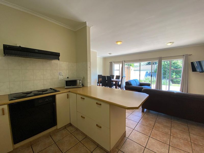 Open-plan kitchen and living area featuring tiled flooring, built-in oven and hob, and sliding glass doors leading to the outdoor space.