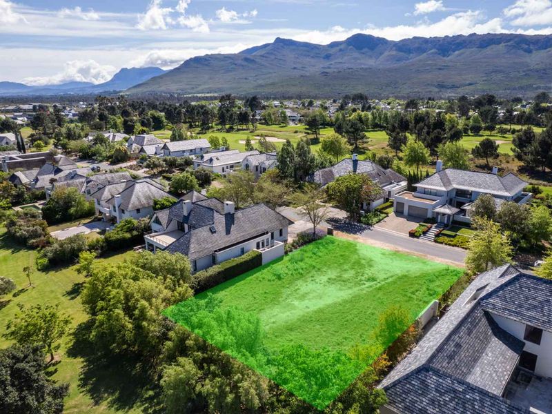 Aerial view of a vacant residential plot situated within an established estate, featuring scenic mountain views and surrounding residential properties.