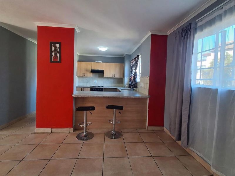 Open plan kitchen and living area featuring a breakfast bar, built-in cabinetry, and ceramic floor tiles.