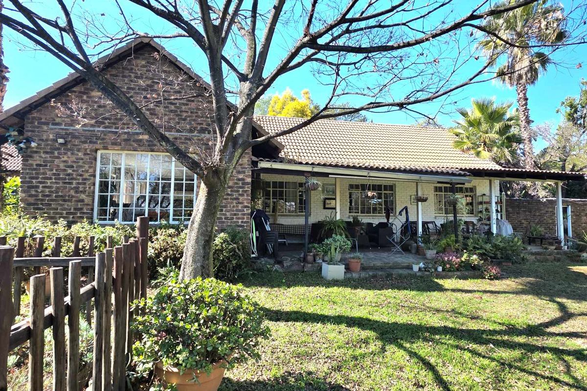 Rear view of a face-brick small holding residence featuring a covered patio area and established garden surroundings.