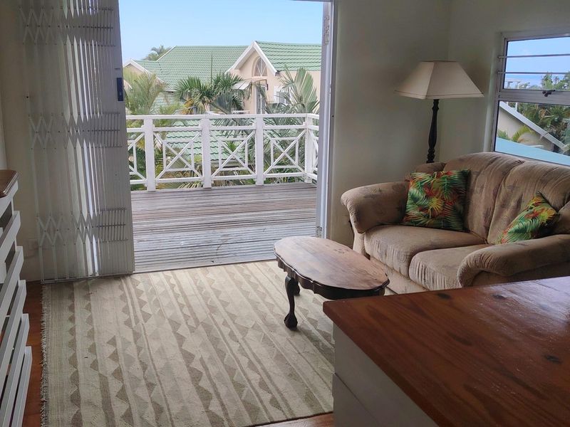 Living room featuring timber flooring and direct access to an outdoor balcony with a balustrade and views of the surrounding estate.
