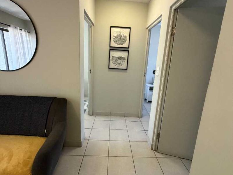 A functional hallway featuring neutral tiled flooring and a tongue and groove ceiling, providing access to adjacent rooms within the apartment.
