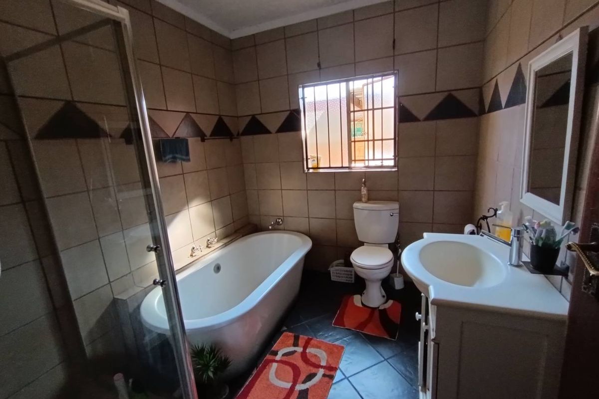 A functional bathroom featuring a freestanding bathtub, glass shower enclosure, vanity basin, and tiled finishes throughout.