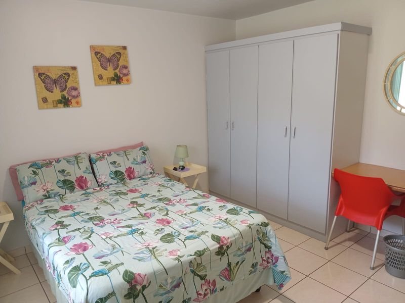 A functional bedroom featuring neutral tiled flooring and a large built-in wardrobe providing ample storage space.