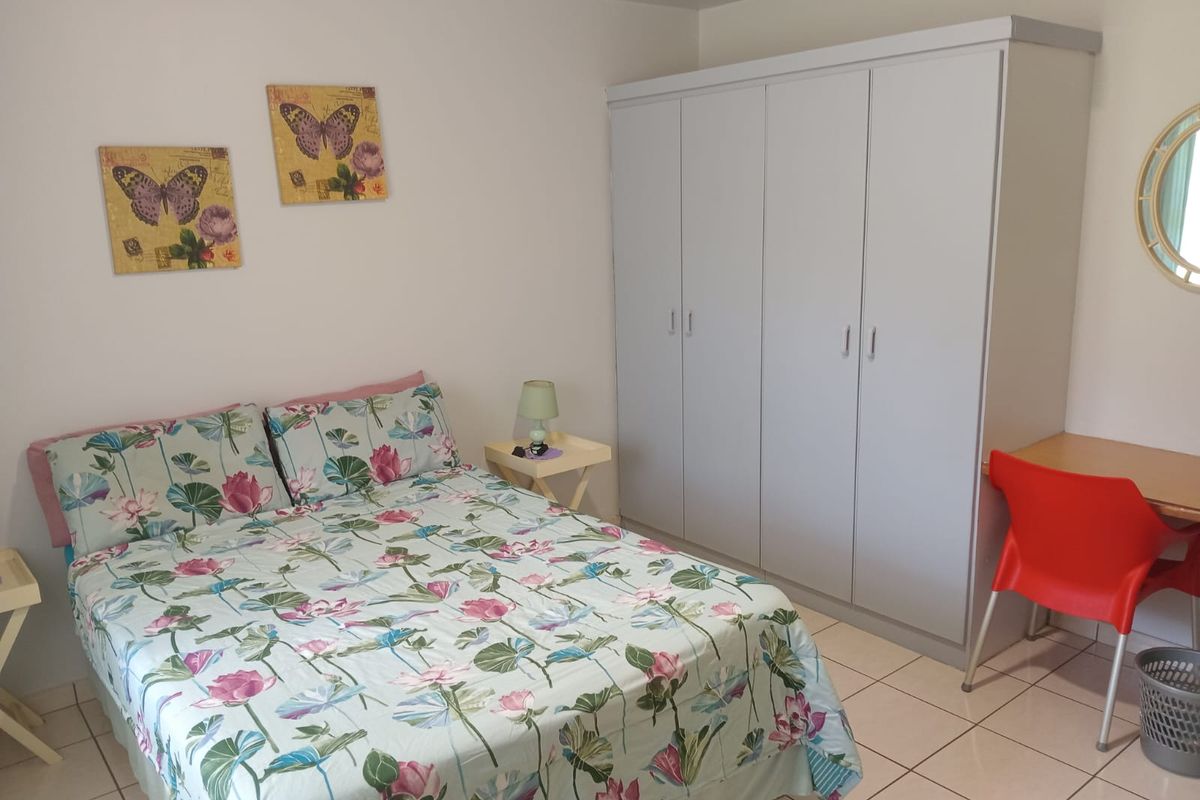 A functional bedroom featuring neutral tiled flooring and a large built-in wardrobe providing ample storage space.