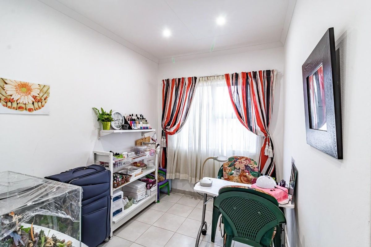 A functional bedroom space featuring tiled flooring and recessed downlighting, currently utilized as a home workspace.