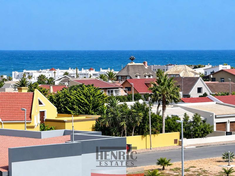 An elevated view overlooking a coastal residential neighbourhood with the ocean visible in the background.