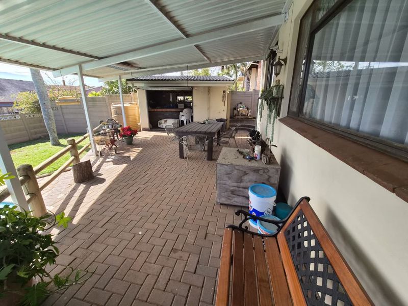 A covered outdoor patio area featuring paved flooring and a corrugated metal roof, providing a functional space for outdoor living and entertaining.