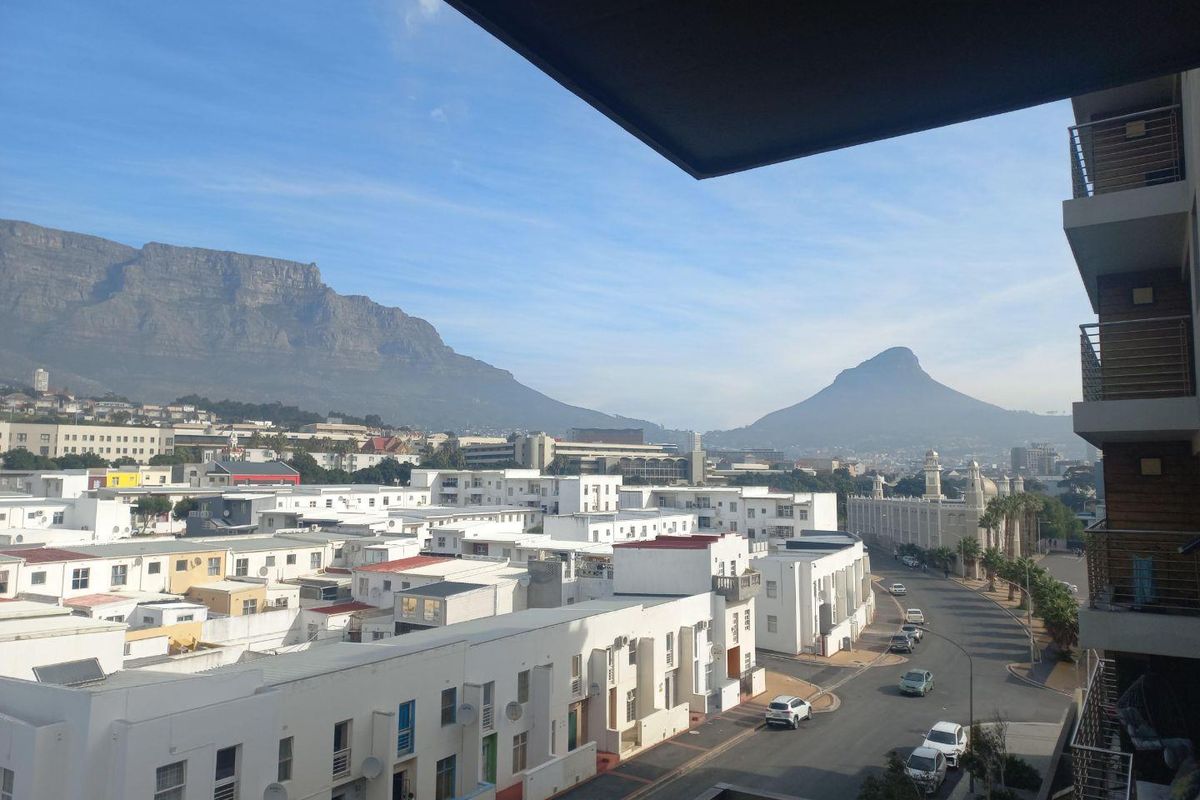 Elevated panoramic view overlooking the city, surrounding residential buildings, and iconic mountain ranges, captured from an apartment balcony.