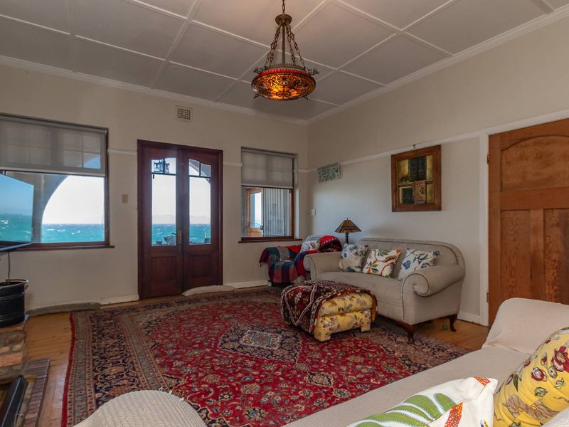 A character-filled living room featuring a brick fireplace, timber-framed doors and windows, and a classic coffered ceiling with ocean views.